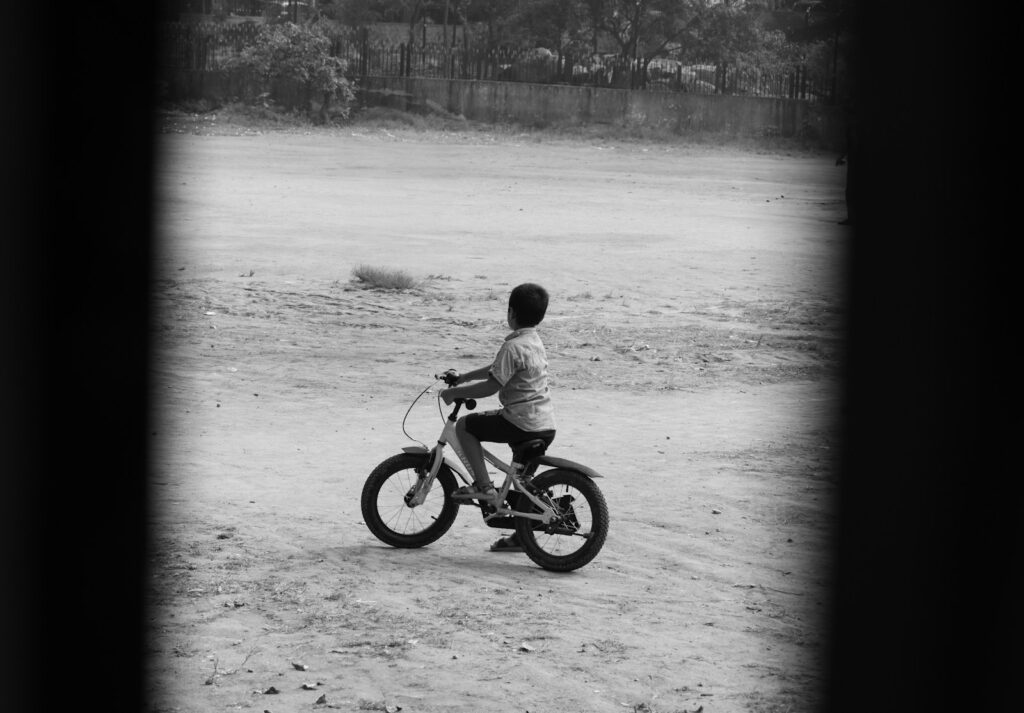 A young boy riding a small motorcycle on a dirt field
