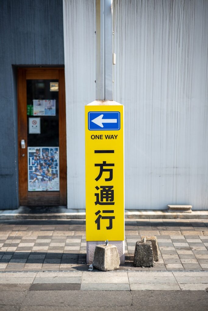 A one way sign on a sidewalk in front of a building