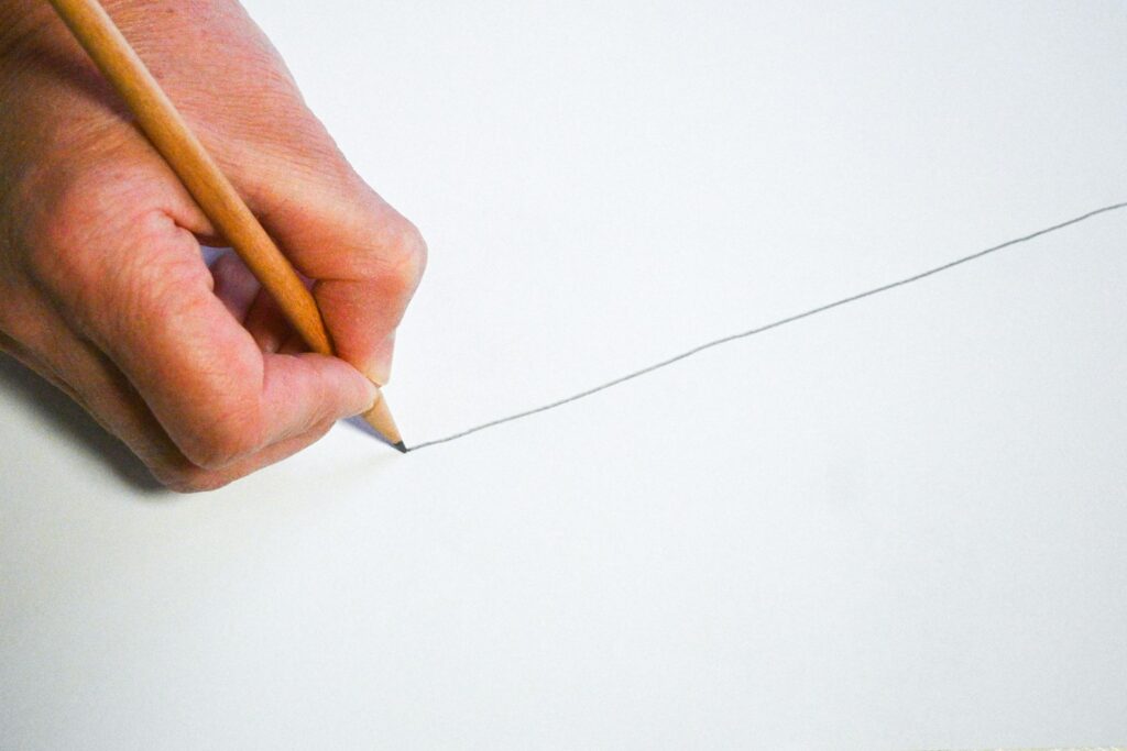 A person holding a pencil and writing on a piece of paper