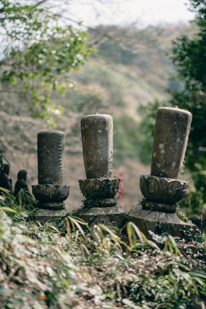 a group of stone statues sitting on top of a lush green hillside